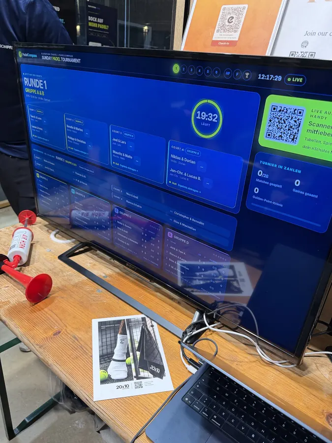 TV-Bildschirm mit dem Live-Turnierplaner und QR-Code für Zuschauer