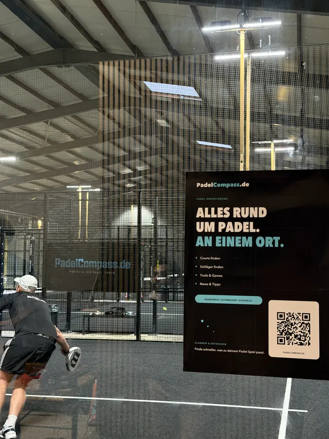 Schlag aus vollem Lauf, im Vordergrund das PadelCompass-Plakat an der Scheibe